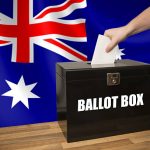 A hand casting a vote in a black ballot box for an election in Australia.